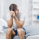 frustrated-man-with-headache-sitting-bed-home